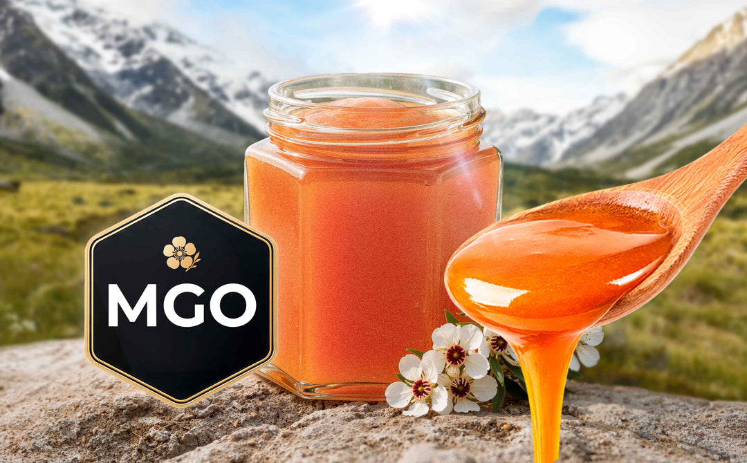 Jar of premium Manuka honey with a wooden spoon drizzling golden honey, displayed alongside an MGO quality badge and Manuka flowers, set against a scenic mountain landscape.