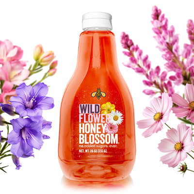 A 26 oz squeeze bottle full of wildflower honey surrounded by wildflowers