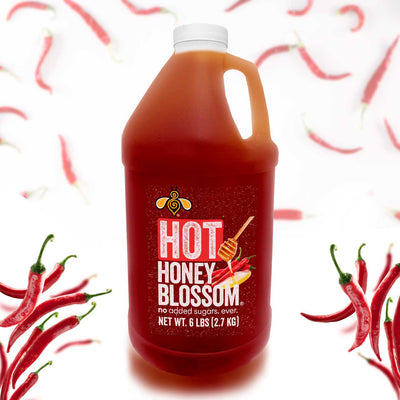 A gallon of hot honey surrounded by cayenne peppers