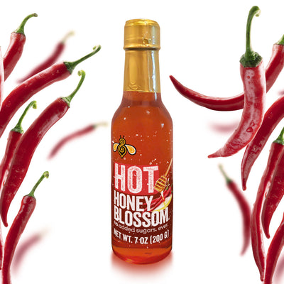 A 7 oz glass bottle, filled with hot honey surrounded by cayenne peppers