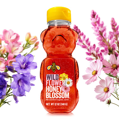 A 12 oz bear bottle full of wildflower honey surrounded by wildflowers