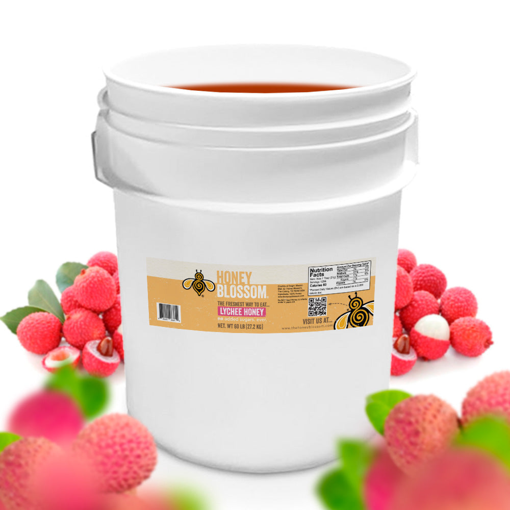 A bucket of light amber honey that is surrounded by lychees