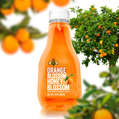 A 13 oz bottle, filled with extra light amber honey, surrounded by Orange trees