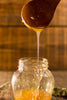 Crystallized honey dripping into a jar