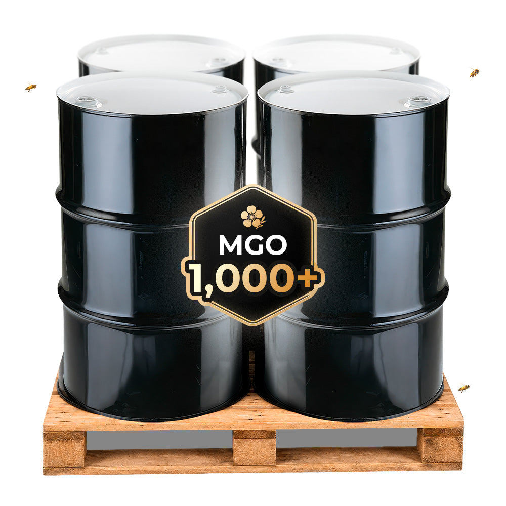 Bulk MGO 1,000+ Manuka honey drums stacked on a wooden pallet, representing high-grade Manuka honey for wholesale and industrial applications.